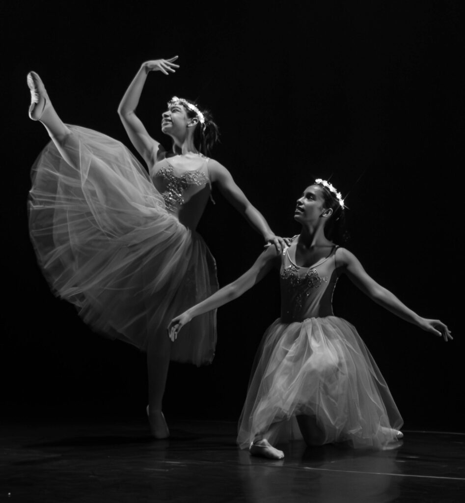 Elegant black and white photo of two ballerinas performing on stage.